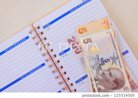 Turkish banknotes lira are laid on an organized planner, showcasing dates planning activities. 125514505
