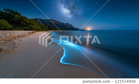 Bioluminescent shoreline with glowing waves beneath starlit sky and forested mountains at twilight horizon 125514956