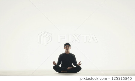 Distant shot of an Asian man in a black suit sitting in lotus pose on a white background Distant shot of an Asian man in a black suit sitting in lotus pose on a white background 125515840