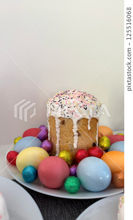 Festive Easter cake decorated with colorful sprinkles surrounded by vibrant eggs 125516068