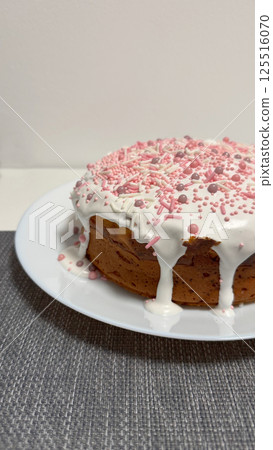 Deliciously decorated cake topped with white icing and colorful sprinkles on a plate Deliciously decorated cake topped with white icing and colorful sprinkles on a plate 125516070