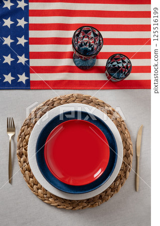 Table setting for USA Independence Day. Festive dinner with empty plate and decoration in USA national flag colors. Copy space. Vertical. View from above 125516199