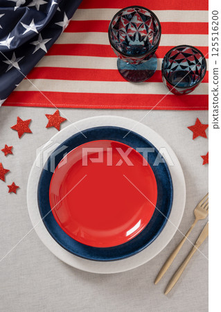 Table setting for USA Independence Day. Festive dinner with empty plate and decoration in USA national flag colors. Copy space. Vertical. View from above 125516200