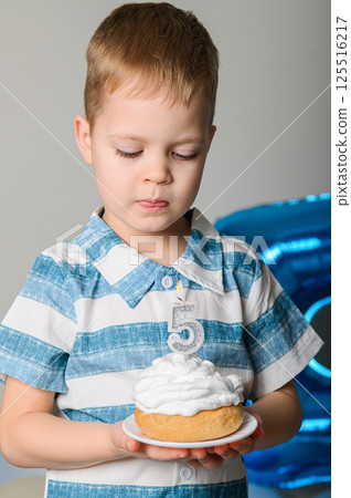 Happy Five Year Old Boy Celebrating Birthday with Cupcake and Candle 125516217