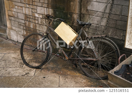 Unused rusty old black bicycle with wooden box parked near dirty brick wall Unused rusty old black bicycle with wooden box parked near dirty brick wall 125516551