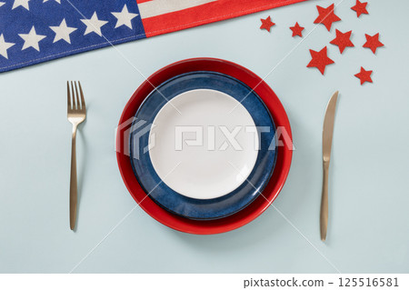 American table setting for USA Independence Day. Festive dinner with empty white plate and decoration in USA national flag colors red and blue. View from above. Copy space. American table setting for USA Independence Day. Festive dinner with empty white plate and decoration in USA national flag colors red and blue. View from above. Copy space. 125516581
