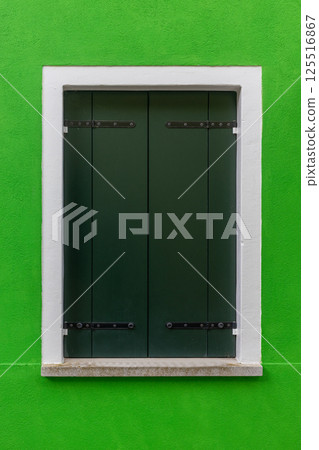 Closed green window shutters on bright green wall Burano Italy 125516867