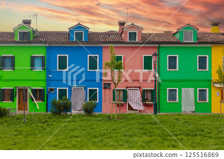 Colorful houses with green lawn and dramatic sunset Burano Italy 125516869