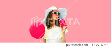 Beautiful young woman model with cup of juice holding balloon summer hat on pink background Beautiful young woman model with cup of juice holding balloon summer hat on pink background 125516958