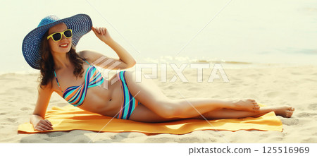 Summer vacation, beautiful happy relaxing young woman in bikini lying on sand on the beach 125516969