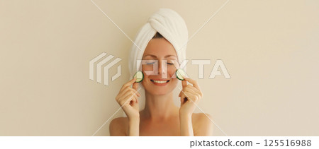 Natural beauty portrait of happy smiling young woman covers her clean skin holds slices of cucumber Natural beauty portrait of happy smiling young woman covers her clean skin holds slices of cucumber 125516988