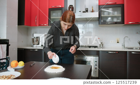 A Young Woman Measures Out Sugar For The Preparation Of A Typical Dessert A Young Woman Measures Out Sugar For The Preparation Of A Typical Dessert 125517239