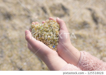 Heart-shaped glass sand collected in the palm of your hand 125518028