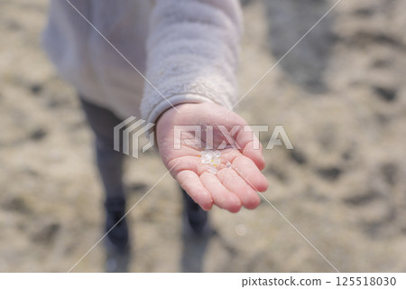 一個女孩的手展示她在玻璃海灘上撿到的一塊美麗的玻璃 一個女孩的手展示她在玻璃海灘上撿到的一塊美麗的玻璃 125518030