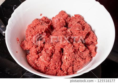 Fresh ground meat in a bowl with a coarse reddish texture, ideal for preparing homemade dishes like burgers, meatballs, or patties. Fresh ground meat in a bowl with a coarse reddish texture, ideal for preparing homemade dishes like burgers, meatballs, or patties. 125518177