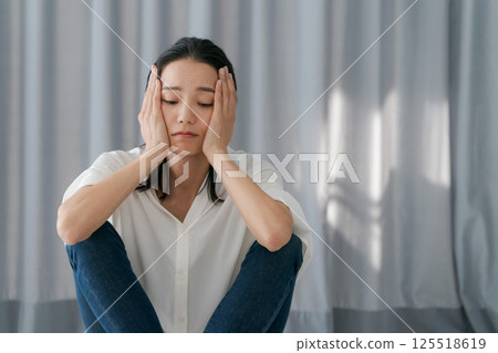 Depressed woman sitting by the window Depressed woman sitting by the window 125518619