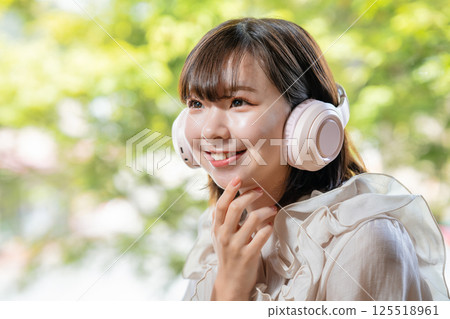 一位年輕女子在綠樹成蔭的房間裡聽音樂 125518961