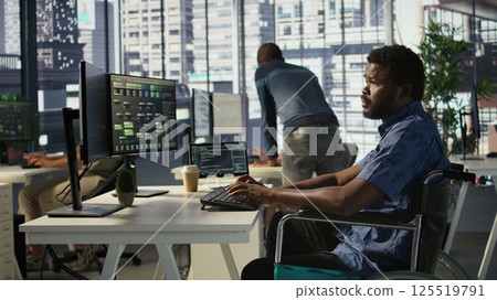 Software technician with disability in inclusive workplace working with machine learning tech. African american IT expert with paraplegia in wheelchair transforms data into predictive models 125519791