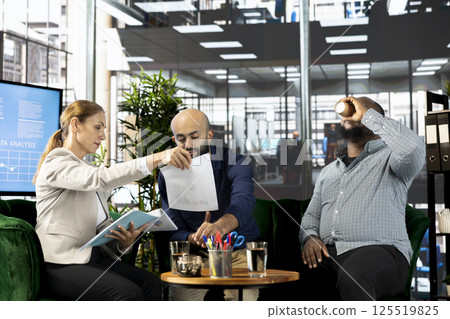 Accountants looking over revenue figures on documents in office. Employees in office focused on comparing company statistical numbers, working hard to finish job before deadline 125519825