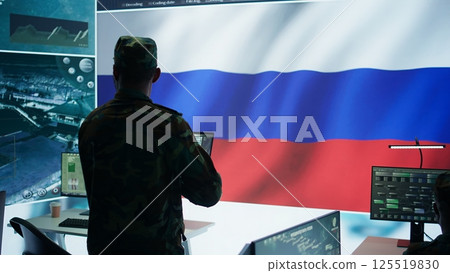 Military expert from Russian army working in governmental base of operations, breaking into rival states servers to spread fake news and hybrid war propaganda. Brainwashing population. Camera B. Military expert from Russian army working in governmental base of operations, breaking into rival states servers to spread fake news and hybrid war propaganda. Brainwashing population. Camera B. 125519830