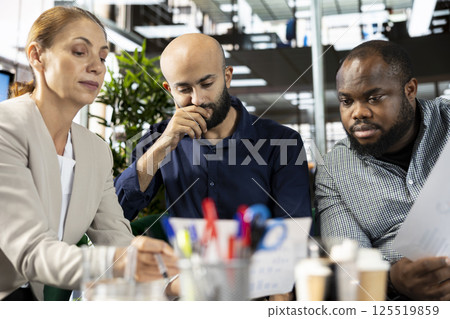 Multiethnic employees in company office checking progress on customer commissioned project. Team of multiracial bookkeepers comparing key data statistics after business audit 125519859