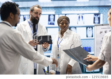 Medical professionals analyzing anatomy x ray scans to find the best treatment, research meeting at facility. Teamwork and expertise in radiology and diagnostics ensure recovery on insurance. Medical professionals analyzing anatomy x ray scans to find the best treatment, research meeting at facility. Teamwork and expertise in radiology and diagnostics ensure recovery on insurance. 125519885