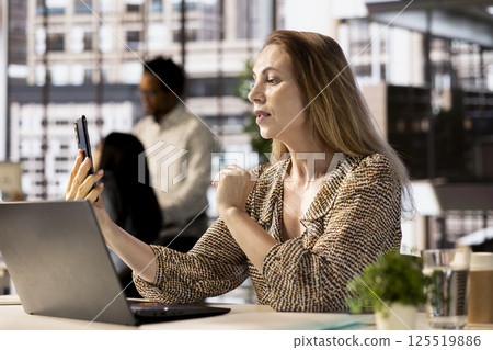 Company manager multitasking during a video call meeting with investors, balancing administrative tasks and project objectives. Fostering online communication for remote business partnerships. 125519886