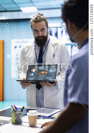 Neuroscience expert reviewing mri brain scan results with doctors, discussing the right treatment plan for disease prevention. Licensed neurologist and his staff examine tomography. 125519889