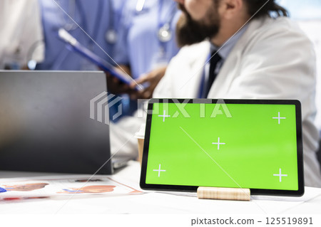 Doctors and nurses review radiography scans with a green screen on desk, discussing potential diagnosis and treatment plans in private clinic. Professional experts staff work with expertise. Doctors and nurses review radiography scans with a green screen on desk, discussing potential diagnosis and treatment plans in private clinic. Professional experts staff work with expertise. 125519891