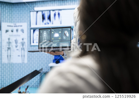 In a treatment center, healthcare experts discuss recovery strategies. Licensed doctors analyze heart and brain x rays from hospital records, focusing on diagnostics and disease prevention. In a treatment center, healthcare experts discuss recovery strategies. Licensed doctors analyze heart and brain x rays from hospital records, focusing on diagnostics and disease prevention. 125519926