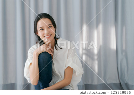 Woman smiling in front of a curtain 125519956
