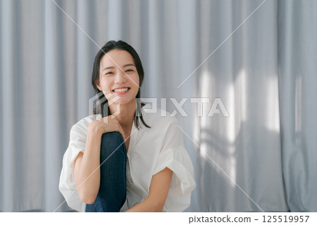Woman smiling in front of a curtain 125519957