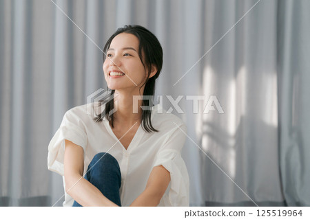 Woman smiling in front of a curtain 125519964