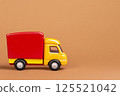 A playful retro fast-food-themed toy truck features bright red and yellow tones on a soft brown backdrop. This charming vehicle evokes nostalgia and whimsy, making it a delightful addition to any 125521042