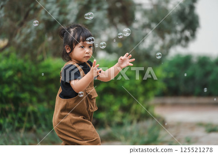 toddler girl playing soap bubble in park 125521278