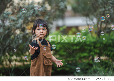 toddler girl playing soap bubble in park 125521279