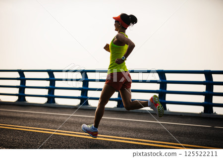 Asian fitness woman runner running on seaside bridge Asian fitness woman runner running on seaside bridge 125522211
