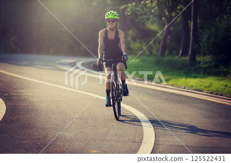 Woman cyclist riding bike at summer park Woman cyclist riding bike at summer park 125522431
