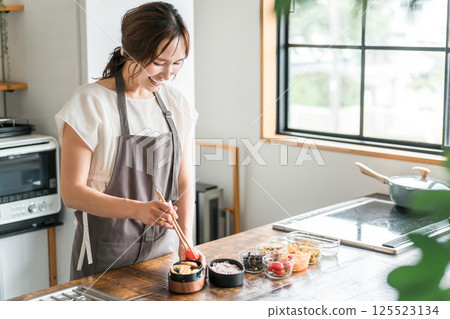 Young Asian woman (mother, wife, housewife) packing lunch in the kitchen Young Asian woman (mother, wife, housewife) packing lunch in the kitchen 125523134