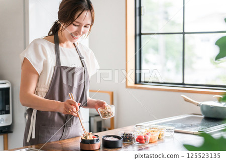 Young Asian woman (mother, wife, housewife) packing lunch in the kitchen Young Asian woman (mother, wife, housewife) packing lunch in the kitchen 125523135