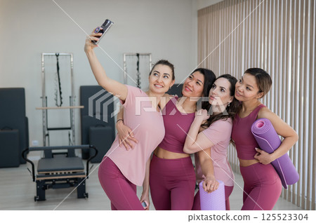 Two Caucasian and two Asian women take a selfie after a Pilates workout. Two Caucasian and two Asian women take a selfie after a Pilates workout. 125523304