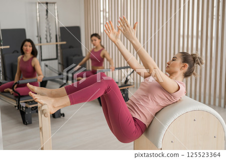 A group of women working out on a reformer and on a Ladder Barrel. A group of women working out on a reformer and on a Ladder Barrel. 125523364