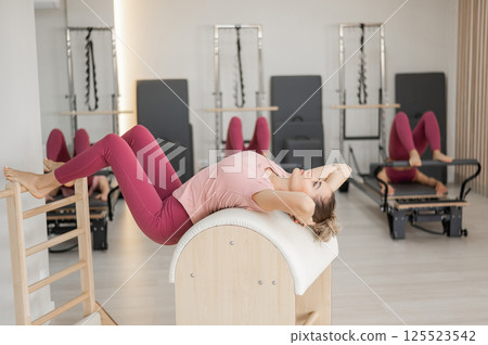 A group of women working out on a reformer and on a Ladder Barrel. A group of women working out on a reformer and on a Ladder Barrel. 125523542