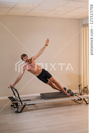 A man doing Pilates on a reformer. A man doing Pilates on a reformer. 125523708