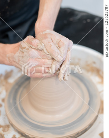 Close-up of a potter's hands working on a pottery wheel. Vertical photo. Close-up of a potter's hands working on a pottery wheel. Vertical photo. 125523797