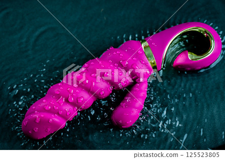Pink ribbed vibrator in water. Circles on water around sex toy. Pink ribbed vibrator in water. Circles on water around sex toy. 125523805