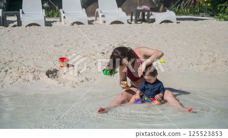 Caucasian woman applies sunscreen to her one-year-old son's skin. Caucasian woman applies sunscreen to her one-year-old son's skin. 125523853