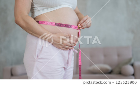 Pregnant woman measuring her belly. Pregnant woman measuring her belly. 125523900