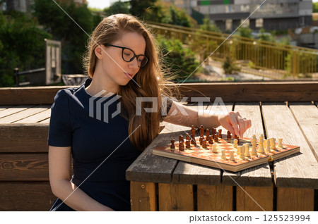 Caucasian woman playing chess outdoors. Caucasian woman playing chess outdoors. 125523994