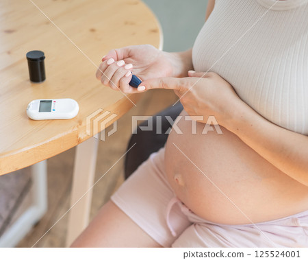 Pregnant woman doing home blood sugar test. Gestational diabetes. Pregnant woman doing home blood sugar test. Gestational diabetes. 125524001